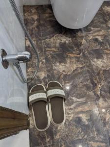 a pair of shoes sitting on the floor next to a toilet at Luxury Designer Studio Apartment Mehar Suites Bahria Self Checkin in Lahore
