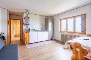 a kitchen and living room with a table and a kitchen at Appartamento Lulù Polsa in Brentonico