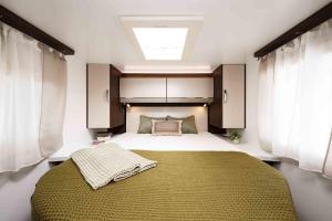 a bedroom with a large bed and a skylight at Lodge Camper am Rursee Deine Eifel Auszeit in Simmerath