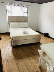 a bedroom with a large bed with a wooden floor at Hotel Colonial El Gran Fénix in Tunja