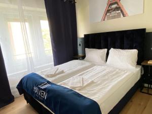 a bedroom with a large bed with a blue headboard at Haven Hotel - Wuppertal in Wuppertal