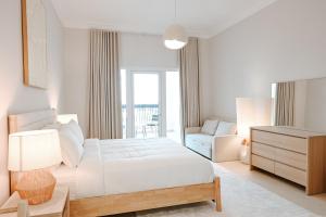 a white bedroom with a bed and a chair at Spacious 2BR in Ansam Yas Island Views Sleeps 7 in Abu Dhabi