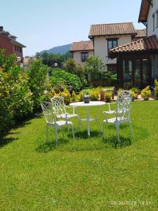 three white chairs and a table in a yard at Cabárceno Chalet vacacional Casa Pedro La Abadilla in La Abadilla