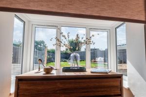a table with a vase of flowers in front of a window at Beach Cottage Pets Welcome Sleeps 6 in Broadstairs +30 photos