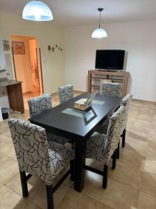 a dining room table with chairs and a television at Apart Dinkendein de 2 dormitorios in Río Cuarto