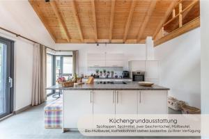 a kitchen with white cabinets and a wooden ceiling at INVITA Natur-Chalets - Gruppenurlaub, Events im Schwarzwald - 6 Apartments, 25 Personen in Bad Dürrheim +43 photos