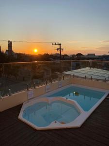 a hot tub on a roof with the sunset in the background at The Reds Pousada in Penha