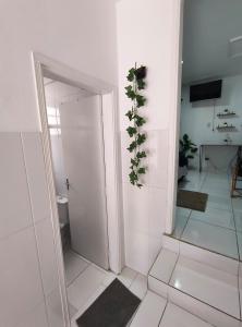 a white bathroom with a plant on the wall at Aconchegante Casa no centro da cidade in Itatiba