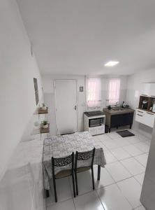 a white kitchen with a table and two chairs at Aconchegante Casa no centro da cidade in Itatiba