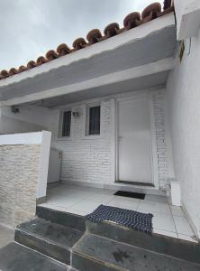 a white building with a door and a tile floor at Aconchegante Casa no centro da cidade in Itatiba