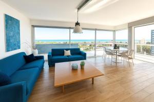 a living room with a blue couch and a table at Penthouse Bellavista in Lignano Sabbiadoro