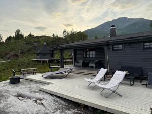 a wooden deck with two chairs and a house at Nittebu in Buvika
