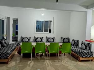 a dining room with green chairs and a table at Dar OUARDA appartement in Tarîfa