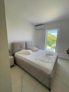 a bed in a white room with a window at Endless blue Apartments in Dhërmi