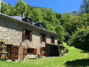 an old stone house with wooden balconies and trees at Les 3 Ours in Couflens