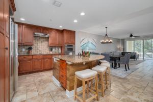 a kitchen with wooden cabinets and a kitchen island with bar stools at 3br L Pool Family & Corporate Travel Sleeps 6 in Palm Coast