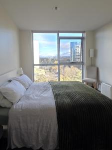 a bedroom with a bed and a large window at The Metropolitan Apartments in Canberra