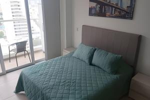 a bedroom with a bed with a green comforter at Apartamento Vacacional sky/el Rodadero in Santa Marta +13 photos
