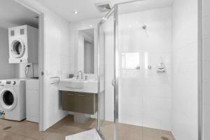 a bathroom with a shower and a sink and a washing machine at The Metropolitan Apartments in Canberra +11 photos