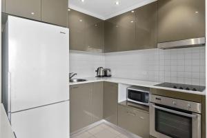 a kitchen with stainless steel appliances and a white refrigerator at The Metropolitan Apartments in Canberra