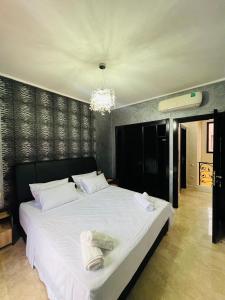 a bedroom with a large white bed with a chandelier at Waky Marrakech Villa in El Rhechat +36 photos