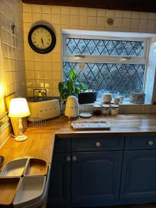 eine Küche mit einer Theke mit einer Uhr an der Wand in der Unterkunft Beautiful apartment at field view cottage in Eccleston