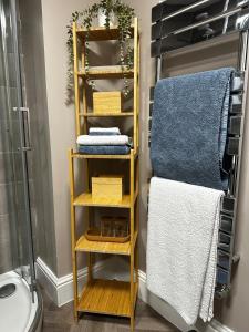 ein Badezimmer mit einem Holzregal mit Handtüchern darauf in der Unterkunft Beautiful apartment at field view cottage in Eccleston + 23 Fotos