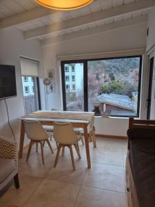 ein Esszimmer mit Tisch und Stühlen und einem großen Fenster in der Unterkunft Para quedarse - SalePatagonia in San Martín de los Andes