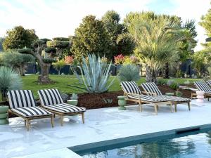 a group of four chairs sitting next to a pool at 537 Saint Emilion - Luxury Guest House in Saint-Laurent-des-Combes