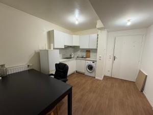 a kitchen with white cabinets and a black table and chairs at Bon77 in Noisiel