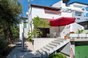 a white house with a red umbrella and stairs at Apartments with parking space Mandre, Pag - 9420 in Kolan