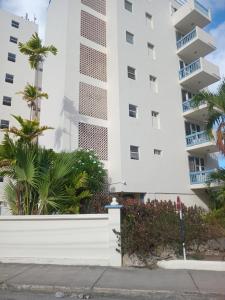 a tall white building with palm trees in front of it at Alleyne Apartments in Bridgetown