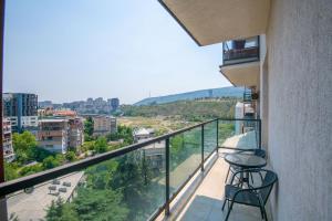 a balcony with two chairs and a view of a city at Cozy stay rentals- cozy & sweet 1 BR apartment in Tbilisi with city & mountains view in Tbilisi City