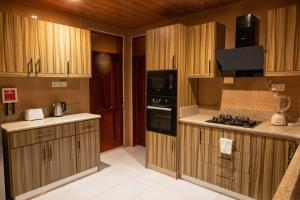a kitchen with wooden cabinets and a stove top oven at Cozy 4 Bedroom Townhouse In Community 25, Tema in Tema