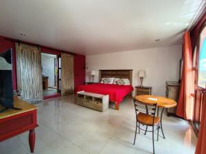 a bedroom with a red bed and a table and chair at HOTEL XIADANI Restaurante, Temazcal & Spa in Tlaxcala de Xicohténcatl