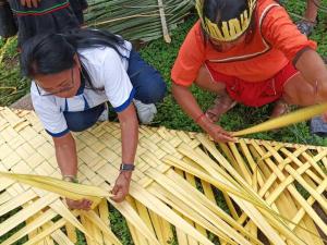 two men are working on a piece of bamboo sidx sidx at San Pablo de Katëtsiaya 