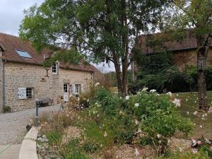 a garden in front of a stone building with flowers at Charmant gîte en Normandie avec jardin et activités à sensations - FR-1-410-300 in Arçonnay