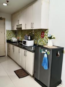 Una cocina con gabinetes blancos y un refrigerador negro. en Sea Residence Tower A by Stave, en Manila