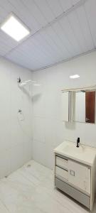 une salle de bain blanche avec une douche et un lavabo dans l'établissement Aliança da Fé, à Cachoeira Paulista