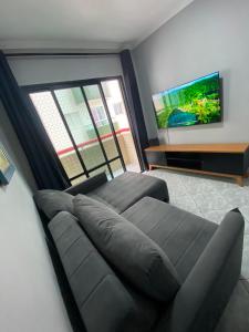 a living room with a couch and a flat screen tv at APÊ VISTA MAR, 20mts DA PRAIA, ESPAÇOSO E ACONCHEGANTE-56m2- WIFI- 1 DORM-ELEVADOR- 6 PESSOAS in Praia Grande +18 photos