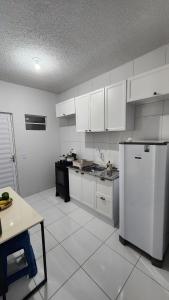 a kitchen with white cabinets and a white refrigerator at Casa aconchegante em Horizonte-CE! in Horizonte