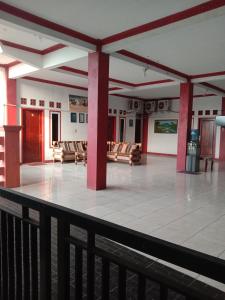 a room with chairs and a balcony with red columns at Penginapan ANGLING DARMA in Cidaun