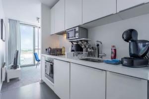 a white kitchen with a sink and a stove at Birmingham Rotunda View by Bull Ring with Free Parking in Birmingham