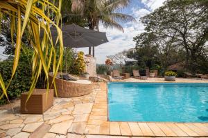 an outdoor swimming pool with an umbrella and chairs at Pousada da Lua São Pedro in São Pedro