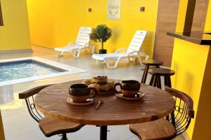 a table with two cups on it with chairs and a pool at Pousada Flor do Campo in Lavrinhas