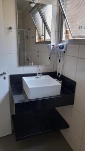 Un baño con un lavabo blanco y un espejo. en Apartamento Frente Praia Embaré - Varanda Aconchegante - Pet Friendly, en Santos
