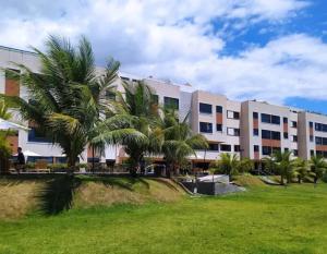 a large building with palm trees in front of it at Apartamento Cobertura em Guarajuba Perto do Mar in Camaçari