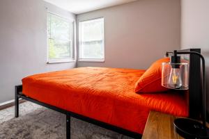 a bedroom with a bed with an orange blanket and two windows at Relaxed 2BR Apt in Moraine with Office Space and Washer & Dryer in Moraine