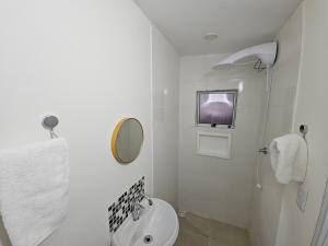 a white bathroom with a toilet and a tv at Loft Nicolau Garcia in São José