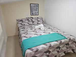 a bedroom with a bed with a green and gray comforter at Loft Nicolau Garcia in São José